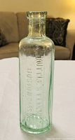 Full view of the pale aqua embossed glass bottle showing shape and embossing