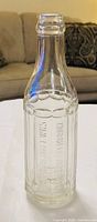 Full view of clear Renfrew Bottle Works soda bottle showing embossed panels and crown lip