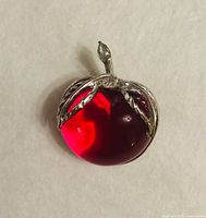 Front view of red lucite apple brooch with leaf and stem detail