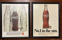 Both framed Coca-Cola ads side by side
