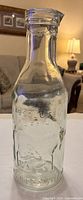 Full view of bottle showing overall shape, neck, embossing, slight green hue