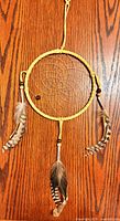 Front view of dreamcatcher showing leather hoop, sinew web, beads and feathers
