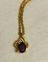 Close-up of pendant showing garnet, clear accent stone and gold-tone setting