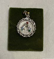 Front view of sterling silver Christmas bell charm pendant on green pad