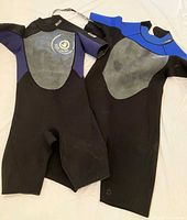 Both wetsuits laid flat showing fronts