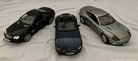 Three 1:18 scale model cars Mercedes SL55 AMG, BMW Z4, Aston Martin Vanquish