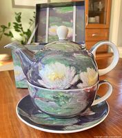 Teapot stacked on cup with saucer, box in background