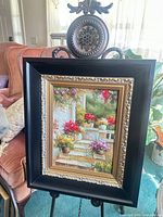 Framed painting on easel showing full frame and artwork
