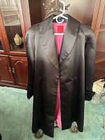 Full front view of black satin coat on hanger showing length and exterior