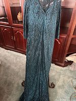 Full frontal view of teal lace evening gown displaying V-neck, sleeve length, lace pattern and full length