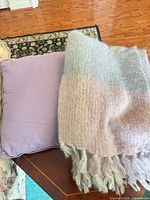 Pillow and folded pastel fringed throw on table