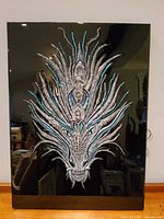 Front view of mixed-media dragon relief on black resin panel