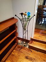 Full view of metal stand holding glass vase with flowers