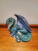 Teal dragon with blue wings on rocky base
