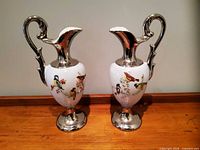 Front view showing both jugs with bird motifs and silver detailing