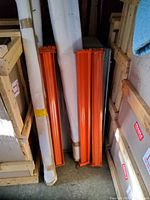 Orange metal beams and wrapped uprights leaning against crates