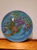 Full view of round plaque showing hummingbird and floral design
