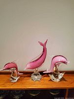 Three pink Murano glass dolphins on shelf