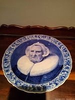 Front view showing portrait, floral border, scalloped rim