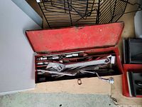 Red metal tray with wrench, sockets, breaker bar, ratchet