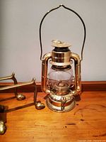 Brass kerosene lantern and portion of andiron