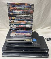 Stack of sealed DVDs positioned on top of four DVD players