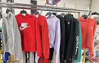 Nine hoodies hanging on rack, front view