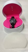 Watch in open white/pink round box with foam removed