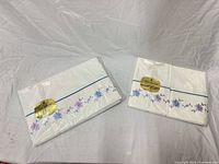 Unopened packages: flat sheet and two pillowcases showing embroidery