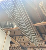 Ten long metal conduit pipes stacked overhead