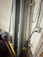 Bundle of tall perforated steel angle irons leaning against a wall