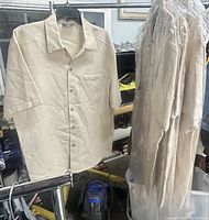 Shirt displayed on hanger next to three packaged shirts