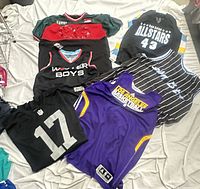 Six jerseys laid out on bed