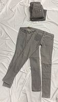 Six pairs of gray jeans, four stacked and two laid out
