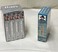 Front view of sealed four-tape box set beside single sealed VHS volume