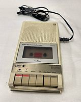 Top view showing recorder, built-in speaker grille, cassette door and control buttons with attached cable