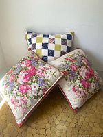 Three pillows arranged; shows designs, shapes and that there are two matching floral and one quilted pillow