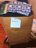 Paper bag with mixed towels, blue geometric border towel visible