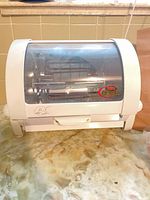 Front view of Baby George rotisserie oven showing glass door and logo