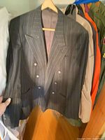 Front view of black pinstripe double-breasted blazer on hanger, showing buttons, lapels and overall condition