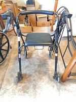 Front view of black rollator walker showing seat, handles, wheels