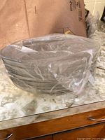 stack of clear glass oval platters wrapped in plastic