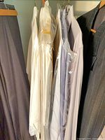 Group of white and striped dress shirts on hangers inside closet
