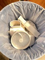 White plastic lid, pusher and perforated disc inside trash can