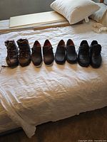 Four pairs of men’s shoes lined up on bed