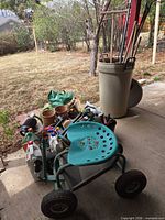 Overall lot on patio: garden scooter, tools can, pots, watering can, hand tools