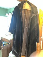 Front view of dark brown faux fur coat hanging, showing length and collar