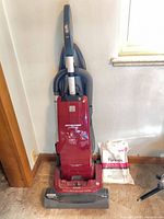 Front view of red Kenmore Intuition upright vacuum with hose, wand and dust bag pack