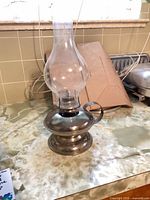 Full view of kerosene lamp with glass chimney on countertop