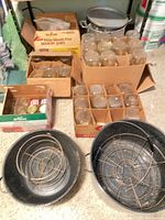 Bulk boxes of mason jars, two black enamel canner pots, wire racks visible